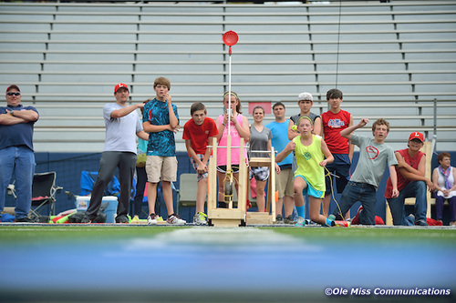 A large group of students watch a demonstration of a catapult