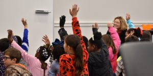 a group of kids all raise their hands as they are asked questions