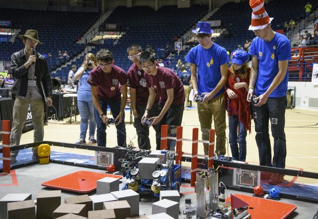 Two teams watch as their robots battle each other
